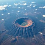 Vista aérea aproximada de cratera de impacto recente na superfície cinzenta e escarpada da Lua.